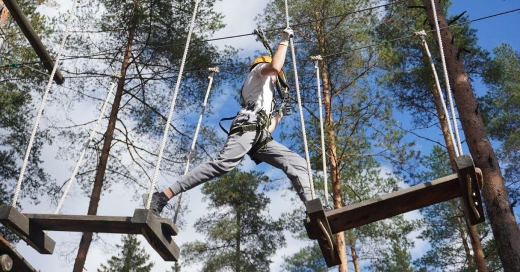 Köysiseikkailu luonnossa – tiimi ylittämässä esteitä puiden välissä
