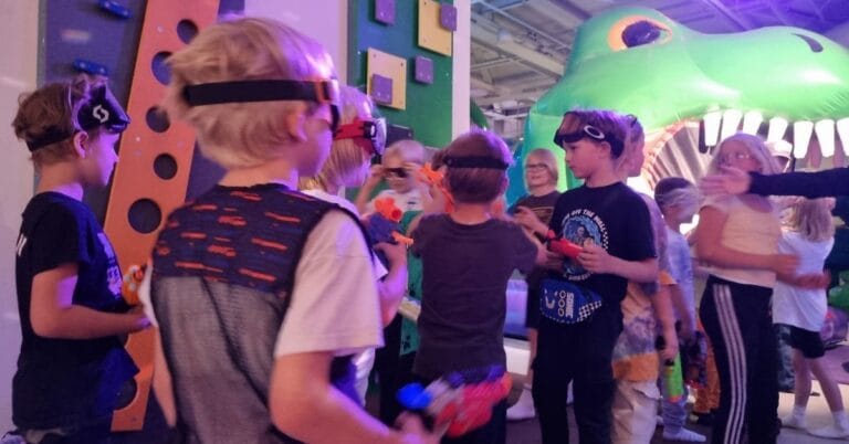 Joukko lapsia pitää hauskaa Pomppulinnaparkisssa