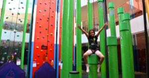 Luokkaretket ja kouluryhmät -artikkelikuvitus - Active Entertainment Nuori tyttö reippaana Irti Maasta-kiipeilykeskuksen tolpilla