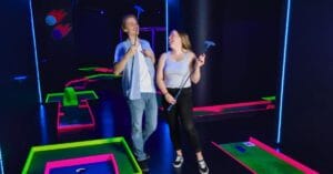 Kaksi nuorta aikuista iloisissa tunnelmissa Hohtogolfissa