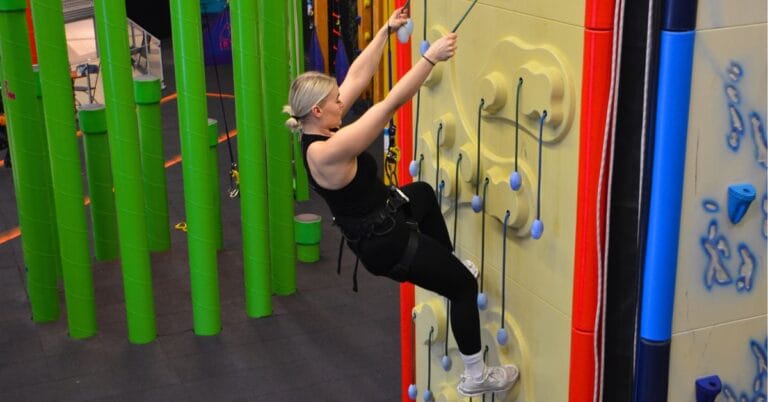 Nuori nainen kiipeilemässä Irti Maasta-keskuksessa