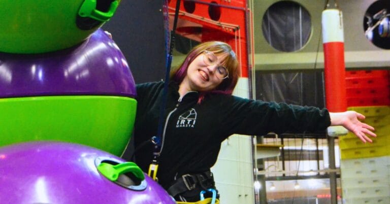 Irti Maasta-keskuksen työntekijä iloisena seinällä